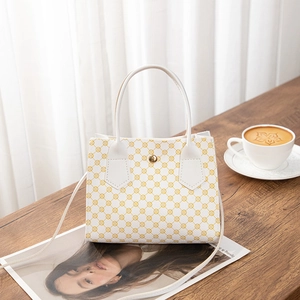 Detail view of white leather handbag with yellow retro prints and golden magnetic clasp