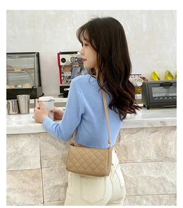 Quilted beige underarm bag styled in a cafe setting with refined stitch detailing
