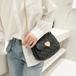 Detail of black quilted crossbody bag with gold heart clasp and chain strap