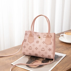 Detail of light pink monogram handbag with heart prints and golden metal magnetic buckle