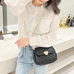 Close-up of black quilted crossbody bag with gold heart lock and elegant chain strap