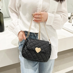 Close-up of black quilted small square bag with golden heart clasp and chain strap