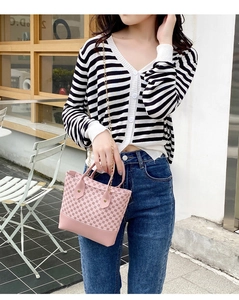 Close-up of pink printed hobo bag with gold chain strap held by a model outdoors