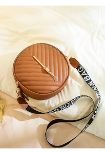 Top view of brown round crossbody bag with V-quilted pattern and golden tassel detail