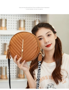 Detail of brown quilted circle crossbody bag with gold tassel and lettered strap