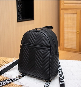 Close-up of black quilted mini backpack featuring colorful letter print ribbon straps