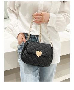 Detail of black quilted crossbody bag with golden heart-shaped clasp and chain strap