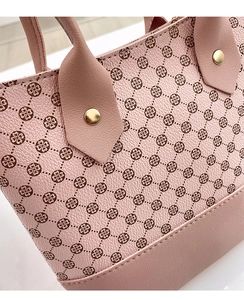 Detail of pink hobo bag featuring clover pattern print and gold rivet hardware