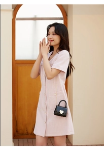 Close-up of model wearing black mini crossbody bag with golden heart clasp and chain