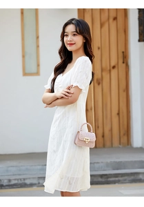 Pink mini jelly bag with studs and gold chain strap shown on a white lace dress