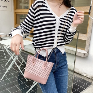 Pink mini tote bag with geometric print and gold chain strap shown on a model