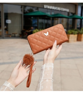 Détail du portefeuille matelassé marron avec décoration papillon blanc et pompon