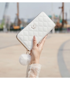 Détail du portefeuille long blanc matelassé avec papillon en métal et pompon en peluche