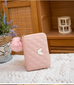 Pink quilted leather wallet with white butterfly metal clasp and fluffy pompom detail
