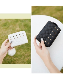 Detail of quilted mini wallet with metallic studs and a fluffy pom-pom keychain