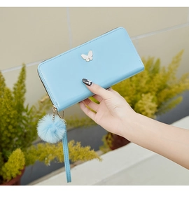 Detail of sky blue glossy long wallet with butterfly decor and fluffy pompom keychain