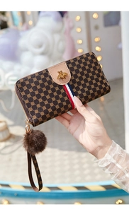 Detail of vintage brown monogram wallet with golden bee emblem and red-white ribbon strap