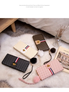 Detail of long contrast color wallet with bee metal logo and fuzzy pompom accessory