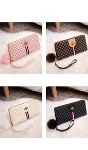 Detail showing long zip wallets in multiple colors with bee logo and pompom charms