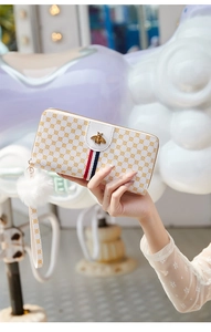 Detailed close-up of a long white leather wallet with gold bee logo and red blue stripes