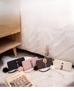 Close-up of long women's wallets with bee detail, ribbon trim, and fuzzy pompom charms