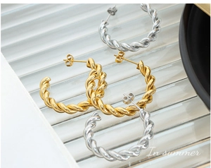 Detail view of twisted rope hoop earrings in polished gold and silver plated finish