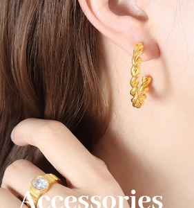 Macro shot of gold twist earrings and a chunky ring with a large oval gemstone