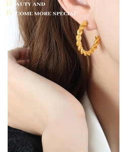 Macro shot of 18k gold plated twisted rope hoop earrings worn on a model ear