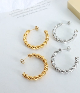 Detailed view of polished gold and silver twisted hoop earrings in minimalist arrangement