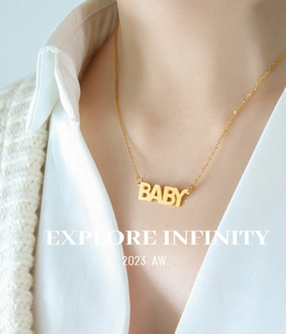 Primo piano di una collana in acciaio al titanio placcato oro 18k con ciondolo BABY