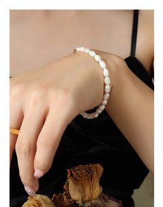 Dettaglio del bracciale con perle d'acqua dolce e chiusura dorata su velluto nero