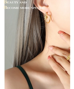 Détail de créoles dorées avec nœud et bague texturée sur un mannequin féminin élégant
