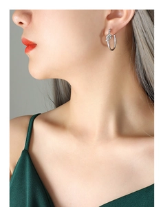 Gros plan d'une boucle d'oreille nœud en argent portée par un mannequin en soie