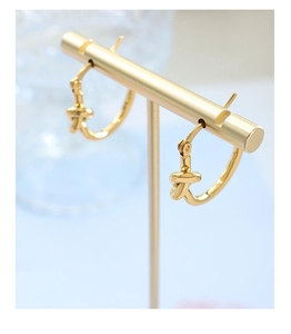 Vue macro des boucles d'oreilles à nœud doré sur un présentoir à bijoux sur fond bleu