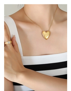 Primer plano del collar con corazón dorado y anillo texturizado con circonita