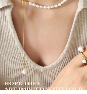 Detailed close-up of a French style pearl necklace and spiral pearl ring on a beige sweater
