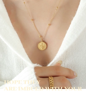 Detail of 18k gold layered necklace with eye pendant and textured ring on female model