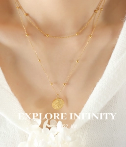 Close-up of 18k gold double-layer necklace with evil eye pendant on a white sweater