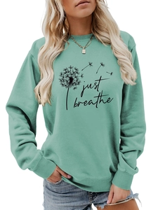 Gros plan sur l'imprimé pissenlit et texte Just Breathe sur le sweat vert menthe