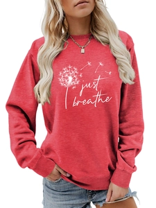 Détail de l'imprimé pissenlit blanc et du texte 'just breathe' sur le sweat-shirt rouge