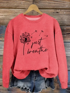 Détail d'un sweat corail à manches longues avec texte just breathe et pissenlit