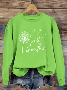 Détail de l'imprimé pissenlit Just Breathe sur un sweat à col rond vert lime sur bois
