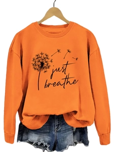 Détail du sweat orange à col rond avec imprimé pissenlit Just Breathe et short en jean