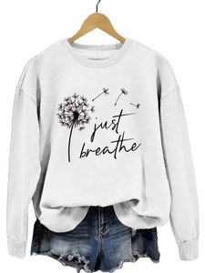 Détail du sweat-shirt blanc à motif pissenlit et texte Just Breathe sur cintre