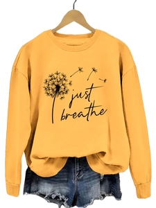 Détail de l'imprimé Just Breathe et du motif pissenlit sur le sweat jaune