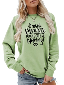Détail du sweat-shirt vert clair avec texte imprimé noir et poignets côtelés