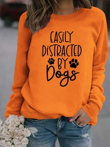Detail of orange sweatshirt with Easily Distracted by Dogs slogan and paw prints