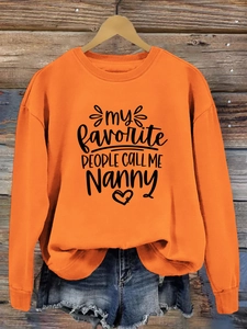 Détail du sweat-shirt orange à col rond avec imprimé noir my favorite people call me Nanny