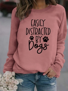 Detailed view of the 'Easily Distracted by Dogs' print on a pink crewneck sweatshirt