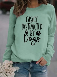 Close-up of mint green crewneck sweatshirt featuring black 'Easily Distracted by Dogs' text